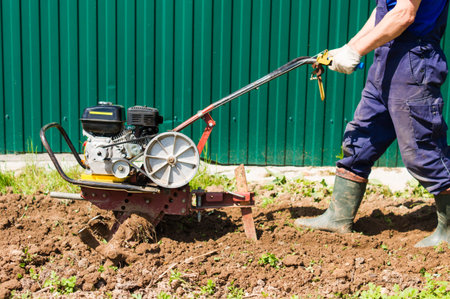 Farmer plows the land with a cultivator. Agricultural workers with tractors. Motor cultivator for...