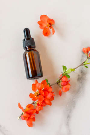 Luxury SPA natural organic skincare products on marble background. Top view dropper bottle with essential oil or aromatherapy massage oil, orange flowers. Body care, skin treatment concept.の写真素材