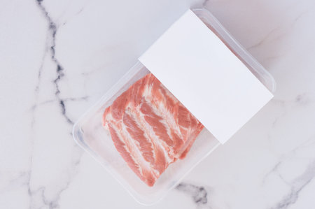 Raw pork ribs in vacuum packaging on marble background, logo mockup for designの写真素材