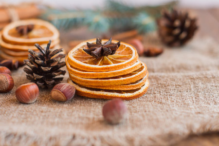 close up of stuck of dried oranges, nuts, anise cloves and cones on rustic burlap. Winter aromatic...