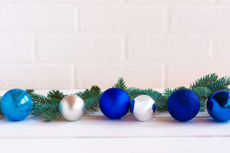Christmas composition with blue and silfer baubles and fir tree brances on white brick wall background with copy space for text.の写真素材