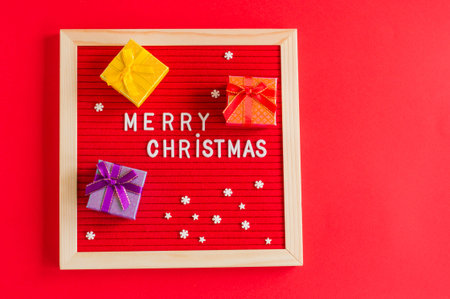 merry christmas festive background with red letter board and small gift boxes and copy space.