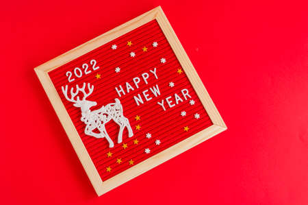Festive new year background. Red letter board with tex happy new year 2022 and deer on red background.の写真素材