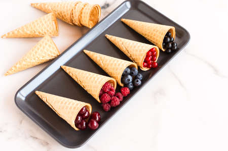 assortment of waffle cones with summer berries on a marble rectangular plate. great dessertの写真素材