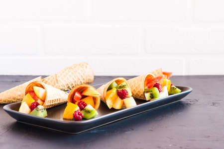 mix of apple, kiwi, orange, grapes in waffle cones.healthy foodの写真素材