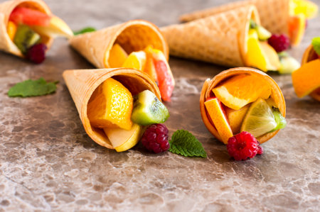 close up of waffle cones with fruit assorty on a marble tableの写真素材