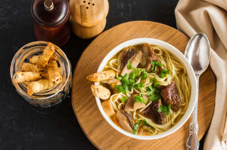 delicious fragrant soup of white mushrooms in a bowl on a round wooden stand. top view. black backgroundの写真素材
