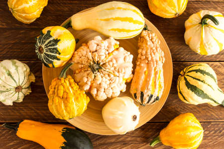 various decorative pumpkins on a bamboo platter on a wooden table. top view. autumn compositionの写真素材