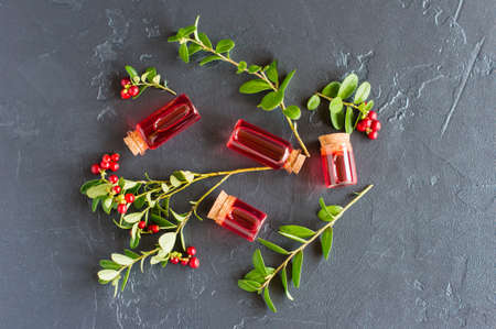 top view of the composition of glass bottles with essential or cosmetic oil from cranberries, cranberry spouts with ripe berries. Selective focus.の写真素材