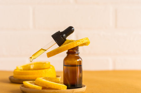 orange oil in a glass bottle and with an oil-filled pipette against the background of citrus fruits...