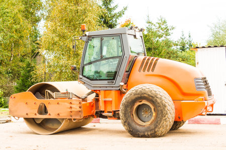 orange asphalt roller in the parking lot before the start of construction work on laying bitumen....