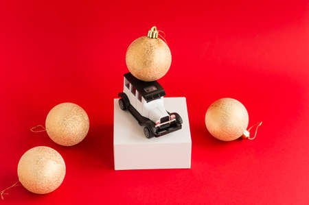 model of a toy white retro car on a red background and Christmas gold balls. the concept of new year holidays, discounts and salesの写真素材