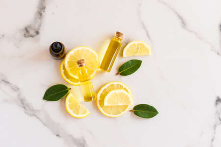 top view of slices of fresh lemon, lemon balm leaves and bright sun essential oil in glass bottles with a cork lid. natural organic cosmetic productの写真素材