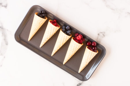 waffle cone with frozen currant berries isolated on white background, concept of juicy ice cream,...