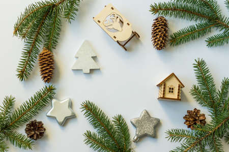 New Year's festive background with cones and green branches, silver stars, wooden sleds and a toy house. flat layout. top viewの写真素材