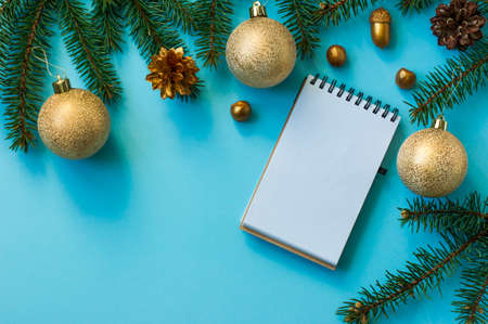 New Year's background with spruce branches, golden balls, nuts, cones, notebook page layout. top viewの写真素材