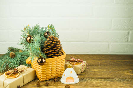 Christmas festive composition on a wooden table. wicker basket with a large cedar cone, spruce branches, gifts and a hot candleの写真素材