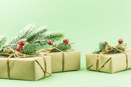 three festive New Year's gifts packed in craft paper with decoration from branches of spruce and...