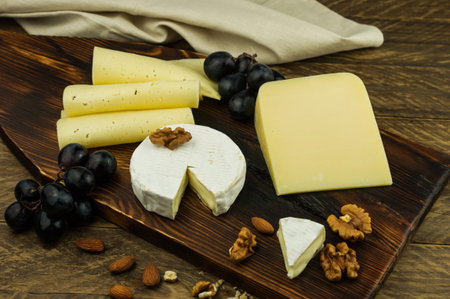 classic Camembert cheese, parmesan, creamy sliisa cheese on a wooden board and a country table