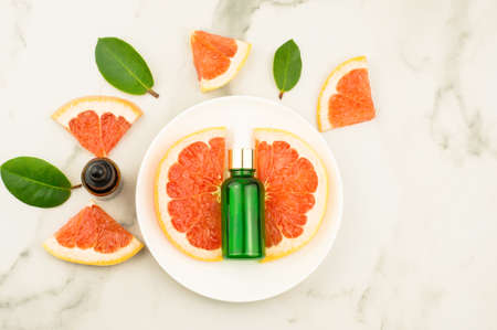 a bottle of essential grapefruit on a white plate and marble table. natural grapefruit, vitamin c. top viewの写真素材