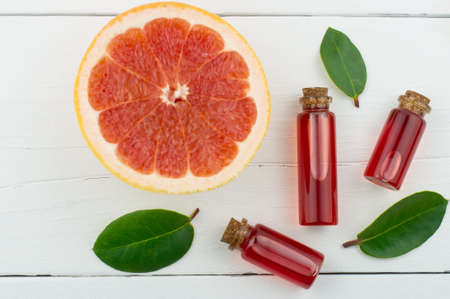 top view of a white wooden background with bottles of or essential oil and half a piece grapefruit. natural organic products of self-careの写真素材