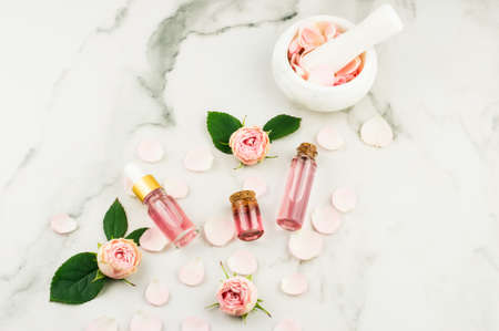 top view of cosmetic and glass bottles with cork lid with rose water and rose essential oil. white background.の写真素材