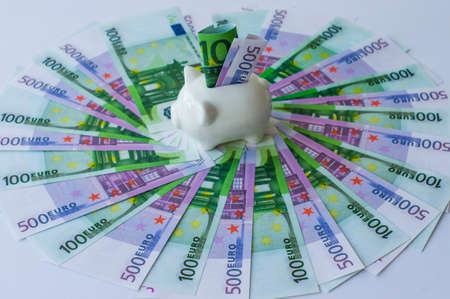 the 500 euro and 100 euro banknotes are fanned out on a lilac background. piggy bank in the center with a folded banknoteの写真素材