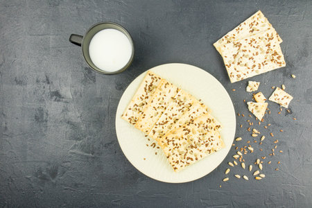 a plate of whole-grain homemade cookies and a mug of milk on a black background. healthy eating. top...