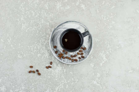 a dark ceramic cup with expresso on a plaster tray with coffee beans stands on a gray concrete table. top view. a copy of the spaceの写真素材