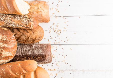 bread background. various types and forms of delicious fragrant bread on white wooden boards with...