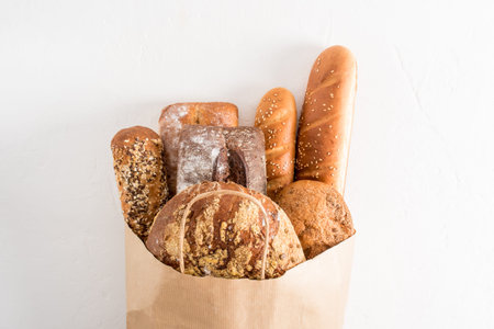 A variety of fresh delicious bread in a paper bag with handles on a white background. the concept of...