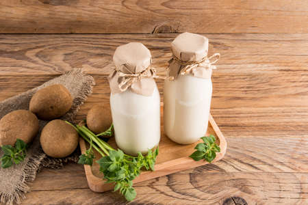 vegan vegetable potato milk in two bottles on a wooden tray and a rustic table. drink substitute. healthy foodの写真素材