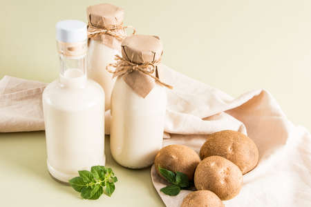 three glass bottles with vegan vegetable milk from potato tubers on a beige pastel background. the concept of healthy eating. drink substituteの写真素材