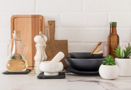 a set of various modern kitchen utensils on a marble countertop against a white brick wall....