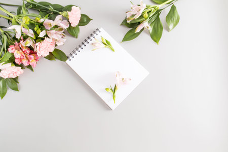 top view of the notepad page for writing your text. pastel background with spring flowers and buds....