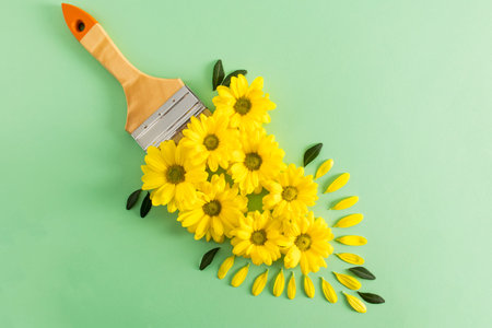creative composition of bright yellow flowers of chrysanthemum and brush on a delicate green background. top view. flat layoutの写真素材