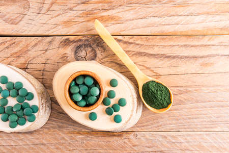 soil of spirulina and spirulina tablets on the background of wooden boards. healthy supplements to strengthen immunity. top viewの写真素材