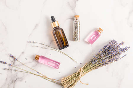 skin care oil, lavender serum, lavender seeds in various bottles on a marble background. top view. flat styling. spa, aromatherapy.の写真素材