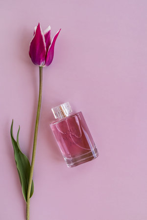 vertical lilac background with a beautiful spring tulip and a crystal bottle of perfume or tualct...