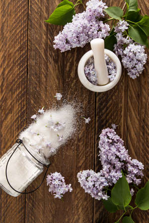 vertical view of a wooden table with branches of garden lilacs and homemade sugar from flowers. delicate aromatic smell of sugar. Perfect for bakingの写真素材