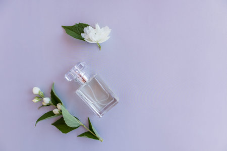 top view of a glass bottle of women's perfume or toilet water with buds and flowers of fragrant...