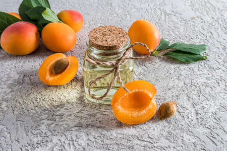 front view of glass bottles with apricot among the apricots. the concept of rejuvenation, nutrition and moisturizing of the skinの写真素材