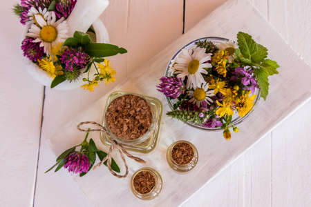 glass bottles of organic St. Johns wort oil stand on a table of white wooden boards. mortar and pestle with grass flowers. alternative medicine.の写真素材