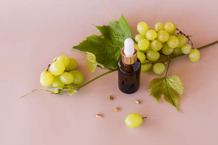 a cosmetic bottle of dark glass with a pipette with organic grape seed oil or a serum for facial skin care. biocosmetics. beige backgroundの写真素材