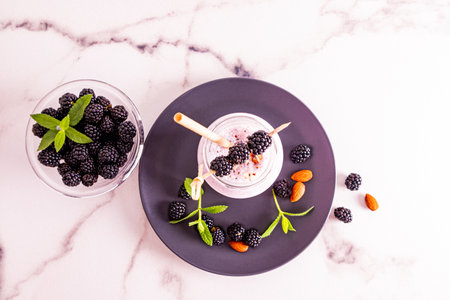 top view of a bottle of freshly made smoothies or a cocktail with nuts and blackberries. marble white background. delicious dessert, snackの写真素材