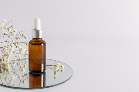 a cosmetic bottle with an amber glass dropper with an eco-natural remedy stands on a round mirror. an empty layout of a cosmetic brand. a copy spaceの写真素材