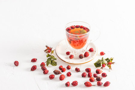 glass cup with double bottom with vitamin hot tea from rose hips on a white background among the berries. useful tea for colds, increased immunityの写真素材