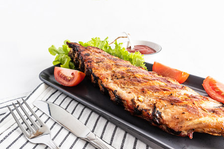 delicious toasted pork ribs on a flat ceramic plate with fresh vegetables. white background. a copy of the space. recipe menuの写真素材