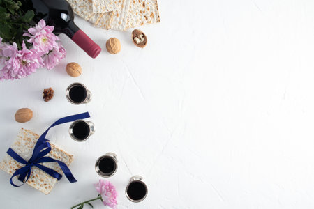 festive background of the Jewish Passover. four silver glasses with red wine, matzah, a bottle of wine, nuts. white textured background. a copy spaceの写真素材