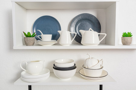 foreground view, close-up of open kitchen shelves with porcelain and ceramic utensils. stylish kitchen background in white tones.の写真素材